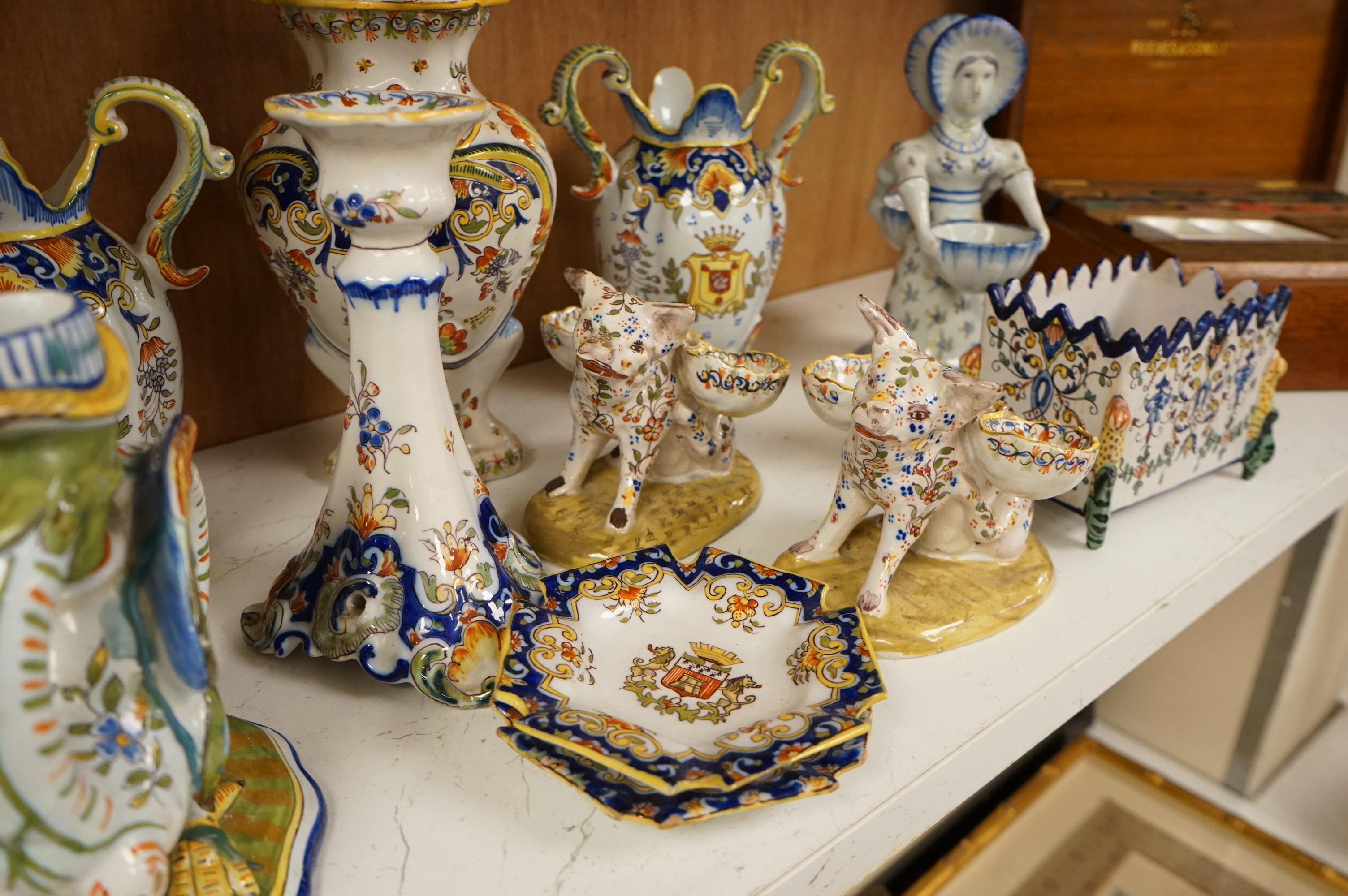 A collection of early 20th century French faience pieces to include a pair of salts in the form of pigs and candlesticks, largest 27cm high